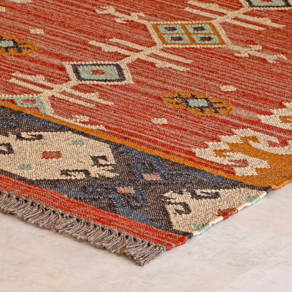 Close-up of a patterned kilim rug with geometric designs on a light background