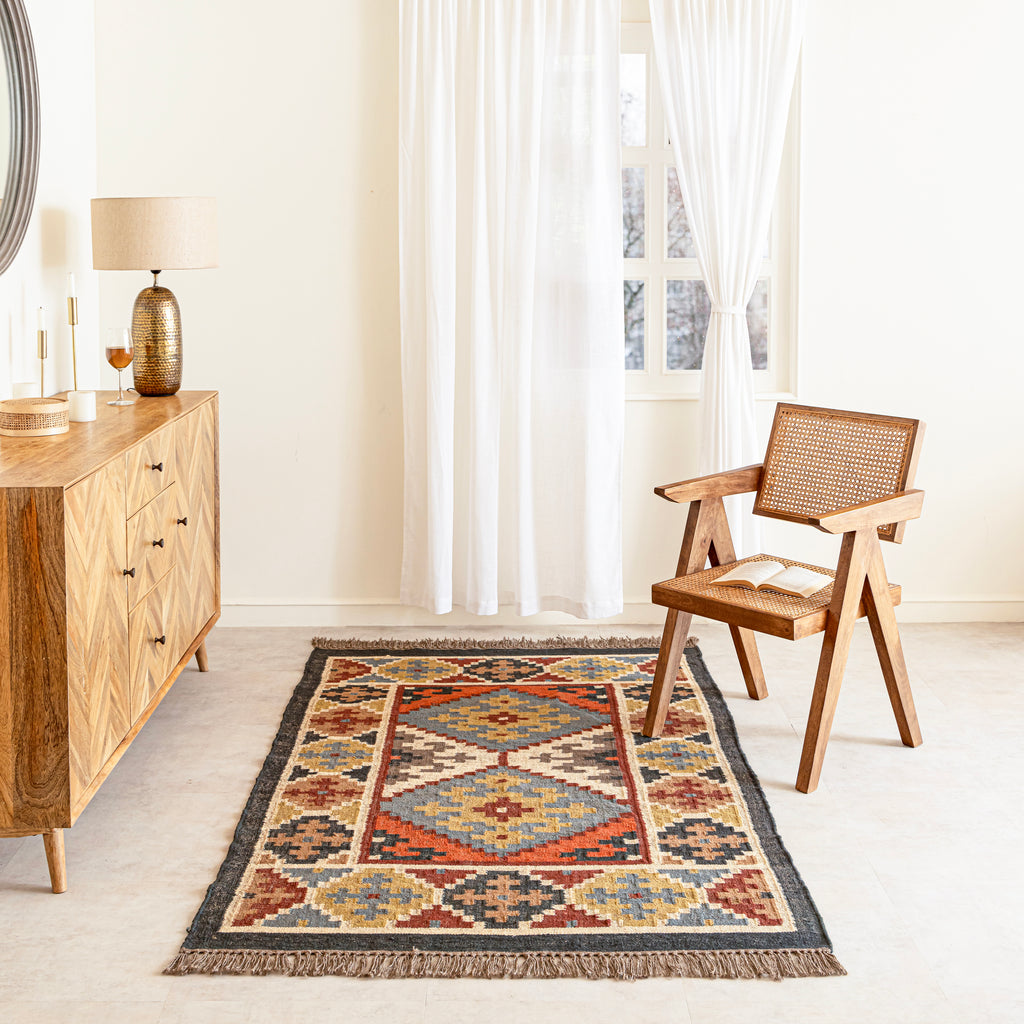 Decorative Jute Kilim rug with geometric pattern in a room with wooden furniture and a chair.