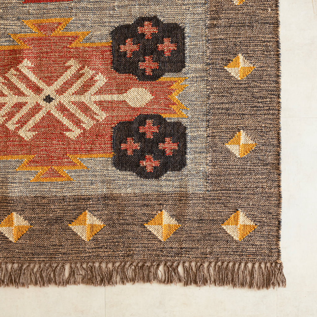 Close-up of a textured kilim rug with geometric patterns on a neutral background