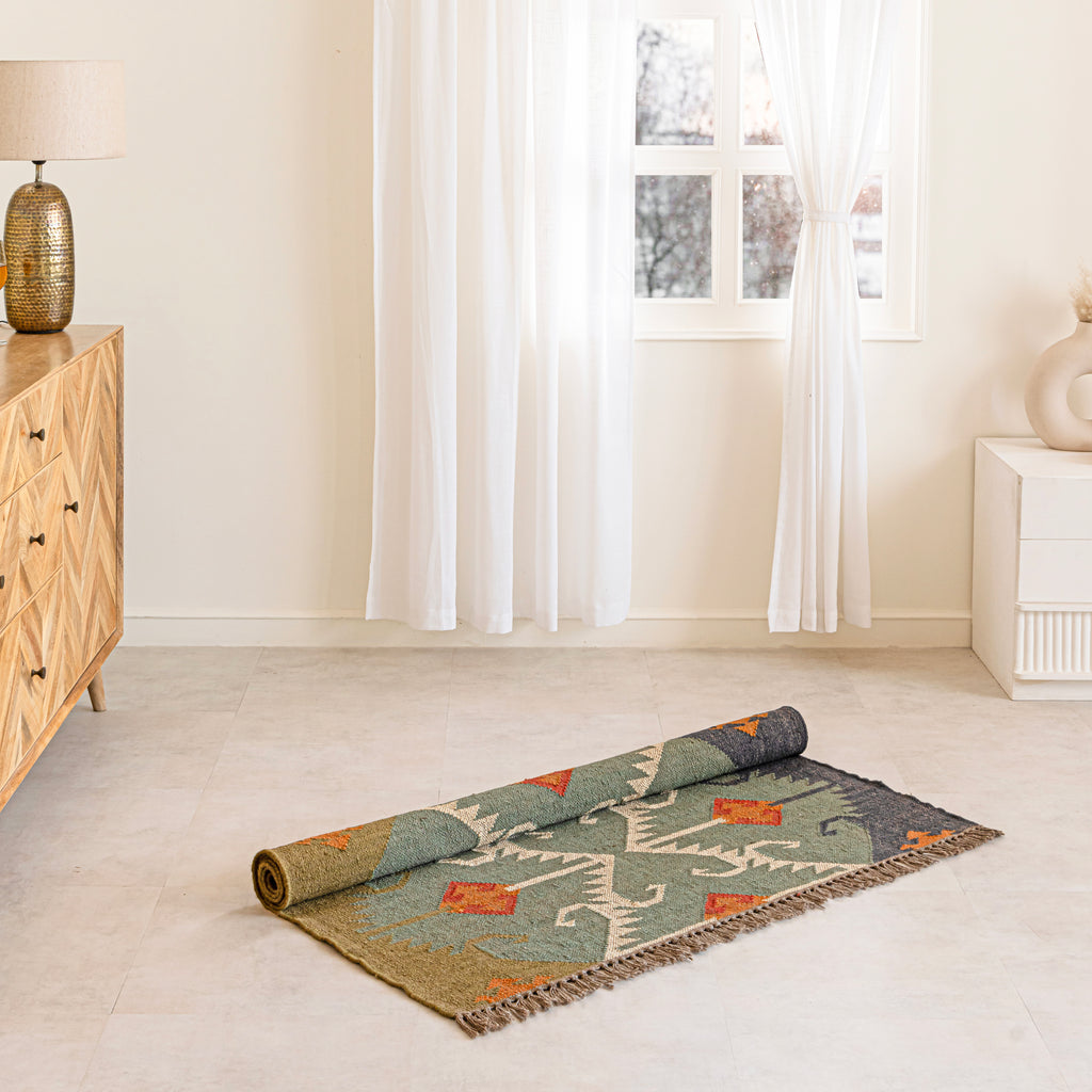 Rolled-up patterned rug on a light wooden floor with a wooden cabinet and lamp in the background.