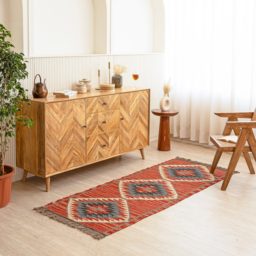 Wool Jute Kilim Rug with aWooden sideboard in a room with a plant and table.