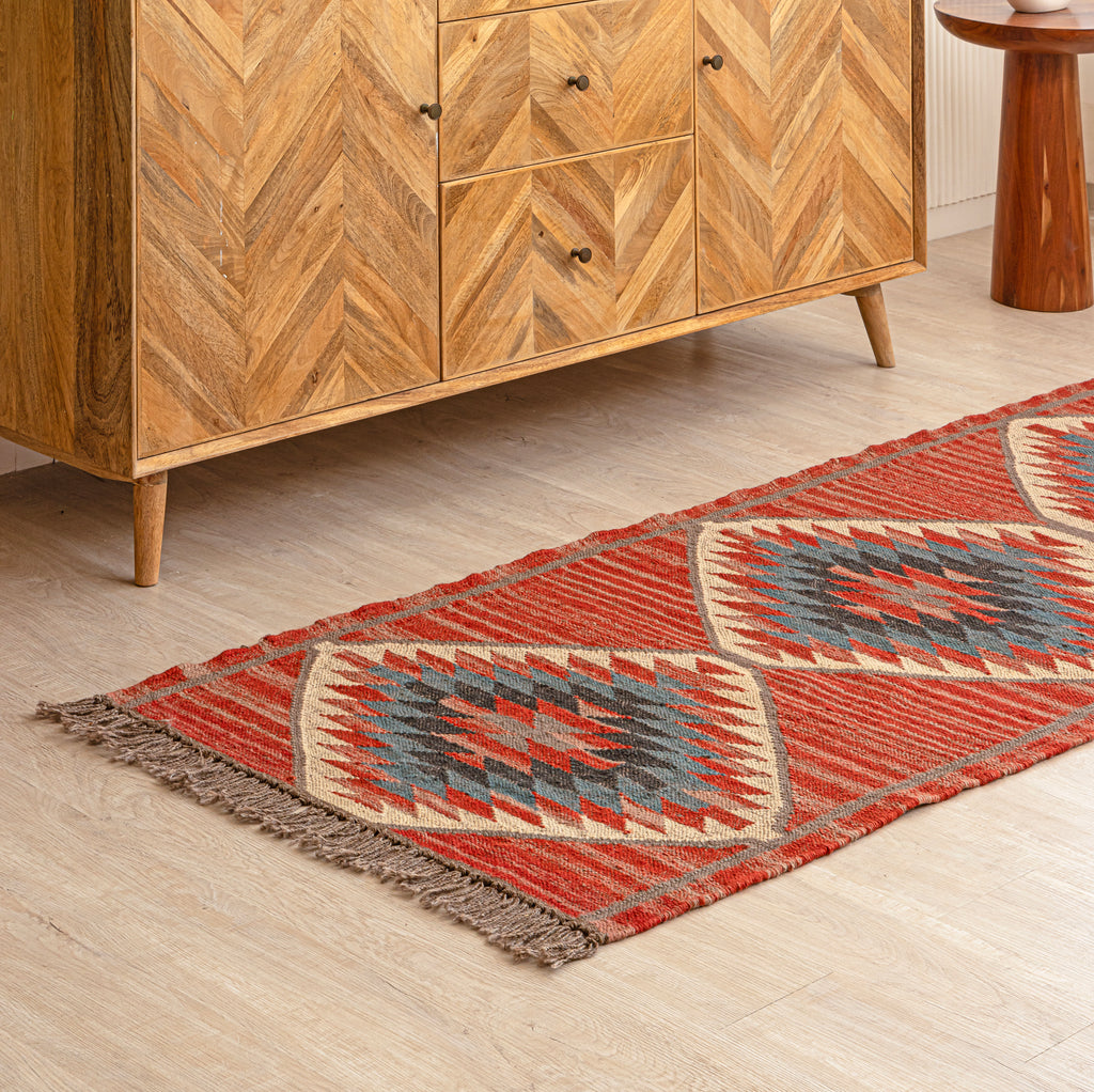 Patterned rug on a wooden floor with a wooden cabinet in the background