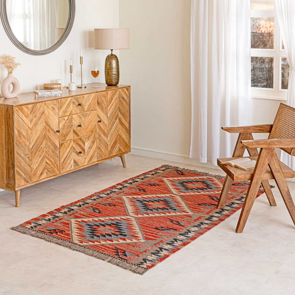 Wool Jute Kilim Rug in Living room with wooden sideboard, and wicker chair.